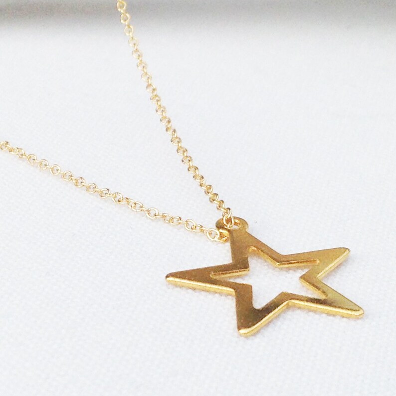May include: A gold chain necklace with a large, open star pendant.