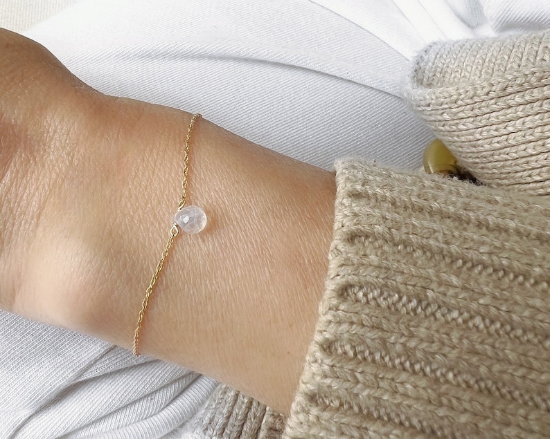 May include: A delicate gold chain bracelet with a single clear quartz crystal charm.