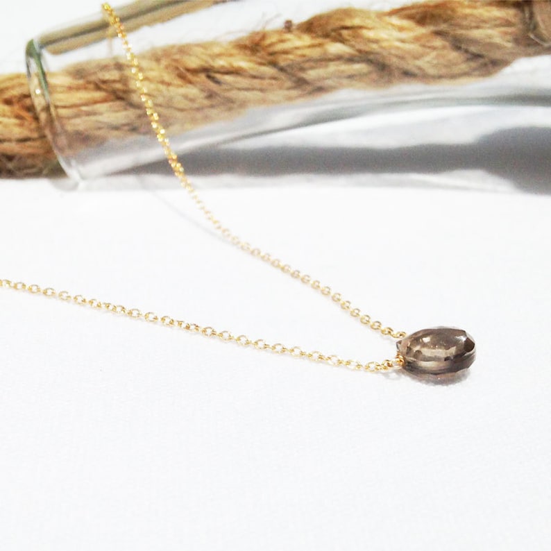 Puede incluir: Un delicado collar de cadena dorada con un peque&ntilde;o colgante de cuarzo ahumado en forma de l&aacute;grima.