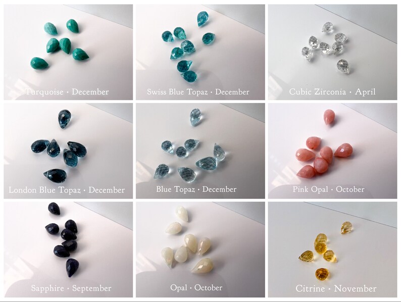 May include: Assortment of teardrop-shaped gemstones in various colours, including turquoise, blue topaz, cubic zirconia, pink opal, sapphire, opal, and citrine. Each gemstone is labelled with its name and corresponding birth month.