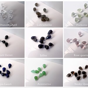 May include: Assortment of gemstone teardrop beads in various colours, including clear, black, blue, green, brown, and pink. The beads are arranged in rows on a white surface. The names of each gemstone are listed below each row.