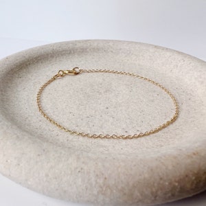 May include: A delicate gold chain bracelet with a lobster clasp.