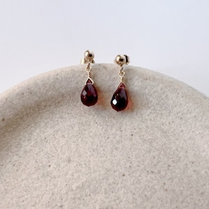 May include: A pair of gold stud earrings with teardrop-shaped red gemstones.