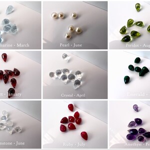 May include: A collage of nine images showing different gemstones in teardrop shapes. Each image is labelled with the gemstone name and its corresponding birth month. The gemstones are aquamarine, pearl, peridot, garnet, crystal, emerald, moonstone, ruby, and amethyst.