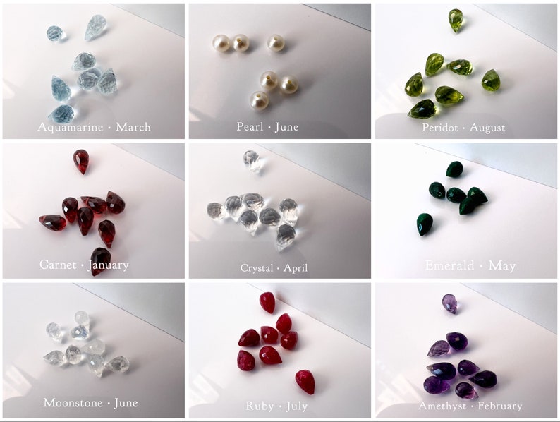 May include: A collage of nine images showing different gemstones in teardrop shapes. Each image is labelled with the gemstone name and its corresponding birth month. The gemstones are aquamarine, pearl, peridot, garnet, crystal, emerald, moonstone, ruby, and amethyst.