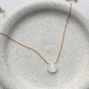 May include: A delicate gold chain necklace with a single, round, white gemstone pendant.