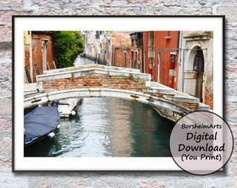Puede incluir: Una vista de un canal estrecho en Venecia, Italia. Un pequeño puente cruza el canal, con un barco amarrado en el lado derecho. Los edificios a ambos lados del canal son antiguos y tienen un encanto rústico.