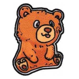 Peut inclure: Un ours en peluche brun dessin animé avec un contour noir, assis les jambes croisées et souriant. L'ours a un contour blanc autour de son visage et un nez blanc.