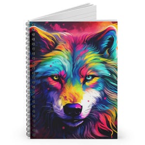 May include: Spiral-bound notebook featuring a vibrant, colorful illustration of a wolf's face. The wolf's fur is depicted in a rainbow of hues, including yellow, blue, green, and pink. The notebook has a white, lined interior.