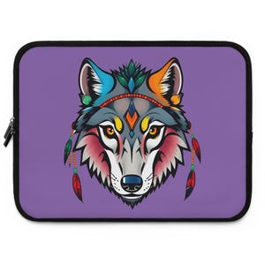 May include: Laptop sleeve featuring a stylized wolf head with Native American-inspired design. The wolf has a colorful headdress with feathers and a geometric pattern. The background is a solid purple color, and the sleeve has a black zipper.
