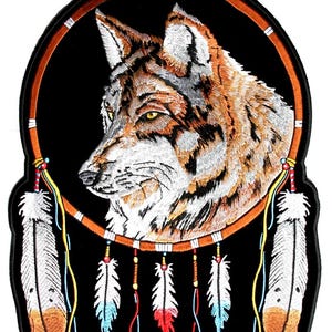 May include: Embroidered patch depicting a wolf's head within a dreamcatcher. The wolf has brown, white, and grey fur with yellow eyes. The dreamcatcher is brown with white, blue, and red feathers hanging below, set against a black background.