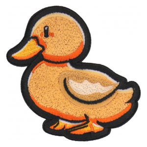 May include: Embroidered patch featuring a yellow duck with orange accents and a black outline. The duck is depicted in a side profile, with detailed stitching creating a textured appearance. This patch is suitable for clothing or accessories.