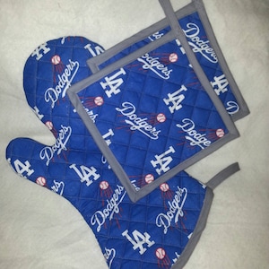 May include: Set of three blue and gray oven mitts with a quilted design and the Los Angeles Dodgers logo. The mitts feature the team's logo, "LA Dodgers", and a baseball.