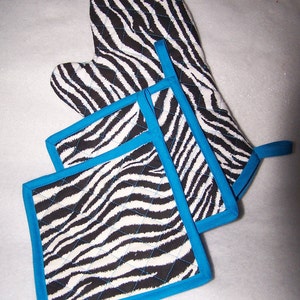 以下が含まれることがあります： 青いトリムが付いたシマウマ柄のキッチン鍋つかみ3点セット。セットにはオーブンミットと鍋つかみが2つ含まれています