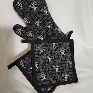 May include: A set of two black oven mitts with a repeating pattern of the Las Vegas Raiders logo and the word "Raiders".