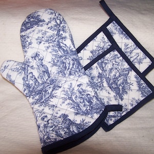May include: A set of blue and white oven mitts and pot holders with a toile pattern. The mitts and holders have a navy blue trim.