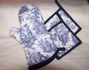 May include: A set of blue and white oven mitts and pot holders with a toile pattern. The mitts and holders have a navy blue trim.
