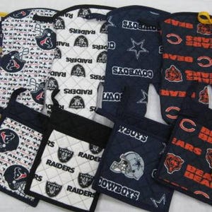 Puede incluir: Una colección de manoplas y agarraderas acolchadas con los logotipos y colores de varios equipos de la NFL. Los diseños incluyen los Vikings, Texans, Raiders, Cowboys, Bears y Chiefs. Las manoplas y agarraderas son de varios colores.