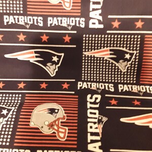 Op de afbeelding: Een herhalend patroon met het woord "PATRIOTS" in het wit, samen met het logo en de helm van het team in rood, wit en blauw. De achtergrond is donker marineblauw met rode sterren en strepen.