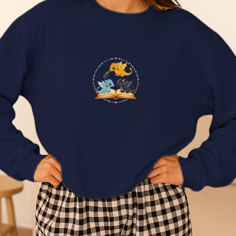 Pu&ograve; includere: Felpa blu navy con un design circolare. Il design presenta tre draghi dei cartoni animati in giallo, blu e nero, sopra un libro aperto. Il design &egrave; circondato da un cerchio tratteggiato con stelle.