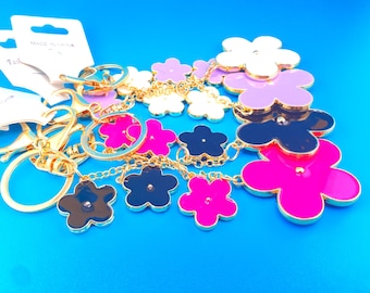 Llavero con dije de flor esmaltada para bolso: herrajes dorados. Disponible en negro, blanco, rosa o morado.