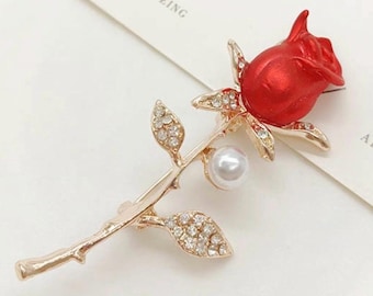 Elegante broche de rosa roja esmaltada con diamantes de imitación y perla, tono dorado, delicado.