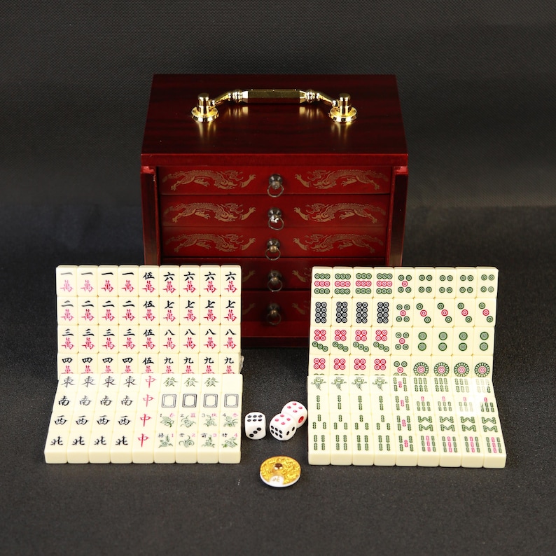 May include: A complete Mahjong set with ivory-colored tiles, dice, and a decorative coin. The set includes a wooden storage box with a handle and gold-colored hardware. The box and tiles feature Chinese characters and symbols.