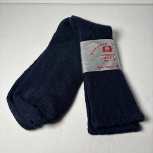 May include: A pair of navy blue socks with a ribbed knit texture. The socks are folded and have a label that reads "If Perfect Fits Sizes 10". The socks are made of cotton.