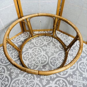 May include: A circular light brown bamboo frame featuring a curved structure with vertical supports and horizontal bracing. The frame is constructed from natural bamboo poles joined together with thin, tightly wrapped bamboo strips at the joints.