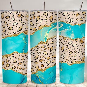 May include: Three stainless steel tumblers with lids and straws. The design features a leopard print pattern, gold glitter accents, and a turquoise marble effect. The tumblers are cylindrical and suitable for cold beverages.
