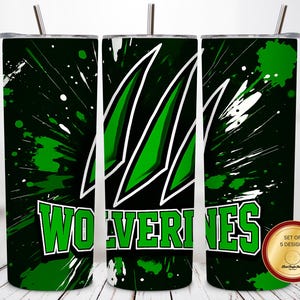 May include: A set of three stainless steel tumblers with lids and straws. The tumblers feature a green and black design with white accents and the word "Wolverines" in green and white. A circular sticker indicates a set of 5 designs.