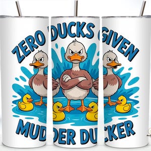 May include: White tumbler with a humorous duck design. The design features three angry ducks and three yellow ducklings in water, with the text "ZERO DUCKS GIVEN MUDDER DUCKER" in blue.