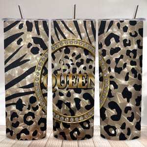 Peut inclure: Trois gobelets en acier inoxydable avec un motif animalier doré, noir et blanc. Le gobelet central porte le mot "QUEEN" en or, entouré d'un anneau doré orné de strass. Chaque gobelet est muni d'une paille argentée.