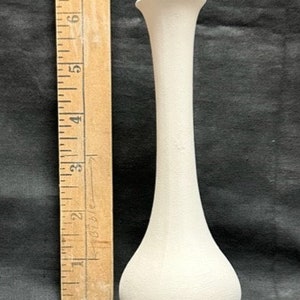 May include: A white ceramic vase with a tall, slender neck and a rounded base. The vase is approximately 18 cm tall.
