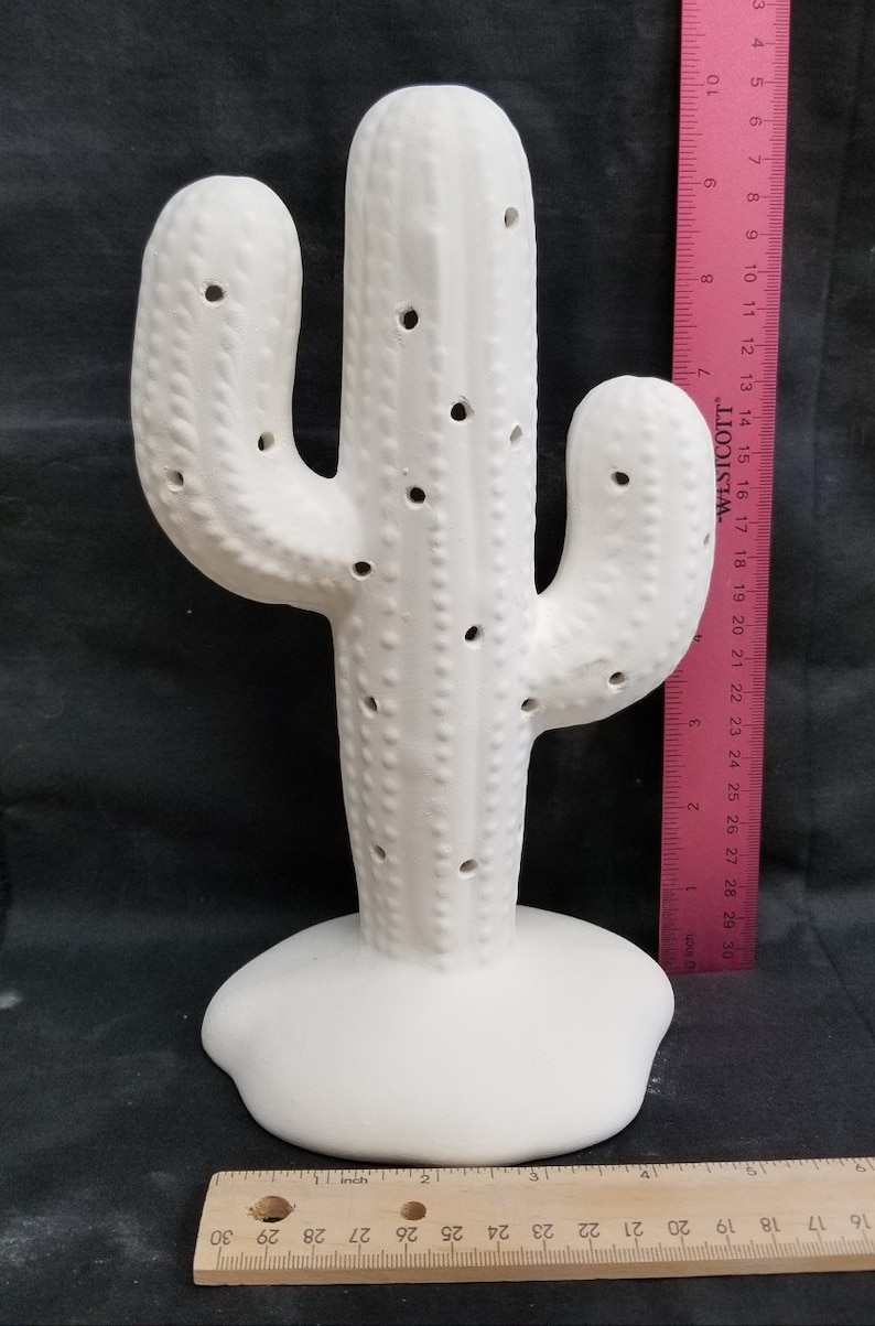 Pode incluir: Figurine de cacto de cer&acirc;mica branca com uma superf&iacute;cie texturizada e furos por toda parte. O cacto tem aproximadamente 45 cm de altura.