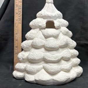 May include: White ceramic Christmas tree with a textured surface and a cutout in the center. The tree is approximately 10 inches tall.