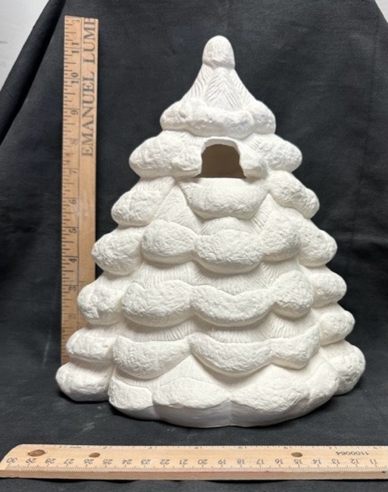 May include: White ceramic Christmas tree with a textured surface and a cutout in the center. The tree is approximately 10 inches tall.