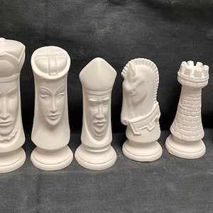May include: A set of six unpainted chess pieces. The pieces include a king, queen, bishop, knight, rook, and pawn. Each piece is white and has a detailed design. The pieces are arranged in a row.