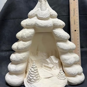 May include: White ceramic Christmas tree with a winter village scene inside. The tree is shaped like a traditional Christmas tree with a pointed top and a wide base. The village scene includes a small house, trees, and a path.