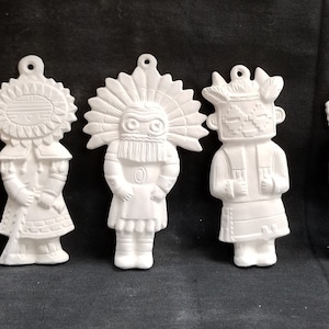 Puede incluir: Cuatro figuras de cerámica sin pintar con forma de figuras nativas americanas. Cada figura tiene un lazo en la parte superior para colgar. Las figuras blancas tienen diseños detallados, incluyendo tocados y ropa.