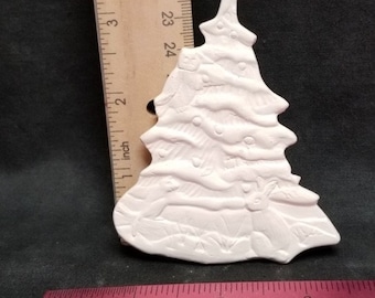 Könnte beinhalten: Ein weißer Weihnachtsbaumschmuck aus Keramik, ca. 7,6 cm hoch. Der Baum hat ein detailliertes Design mit erhabenen Elementen. Der Schmuck ist unbemalt und kann individuell gestaltet werden. Ein Lineal liegt neben dem Schmuck.
