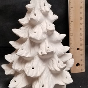May include: White ceramic Christmas tree with a textured surface and holes for lights. The tree is approximately 7 inches tall.