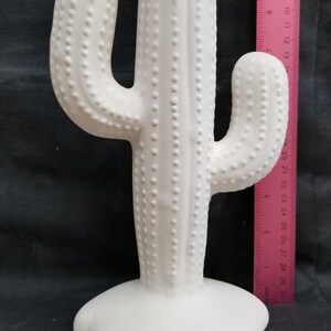 Pode incluir: Escultura de cacto de cer&acirc;mica branca com uma superf&iacute;cie texturizada. O cacto tem aproximadamente 33 cm de altura e uma base larga.