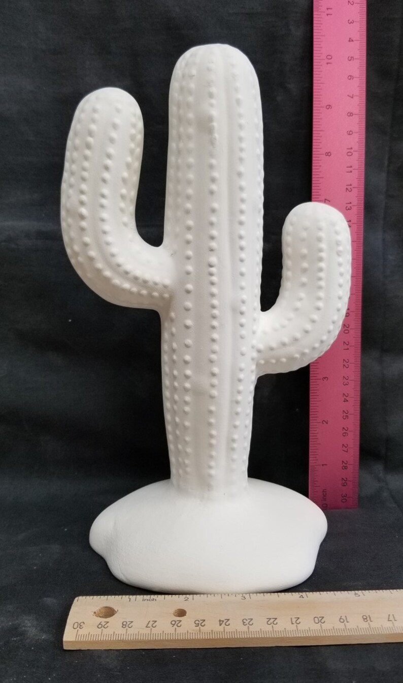 Pode incluir: Escultura de cacto de cer&acirc;mica branca com uma superf&iacute;cie texturizada. O cacto tem aproximadamente 33 cm de altura e uma base larga.