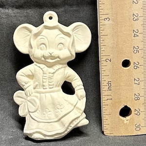 May include: White ceramic ornament of a mouse wearing a dress and holding a shamrock. The ornament is about 5 inches tall.