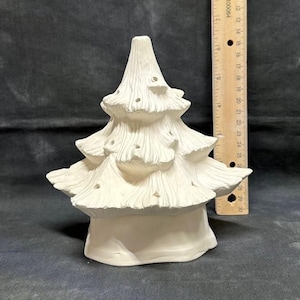 Może przedstawiać: Biała ceramiczna choinka z teksturowaną powierzchnią i małymi otworami na światła. Drzewko ma warstwowy design i ma około 20 cm wysokości.