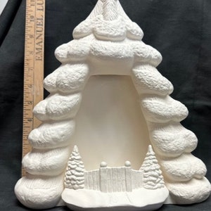May include: White ceramic Christmas tree shaped picture frame with a snow-covered fence and two small pine trees at the base. The frame is ready to be painted.