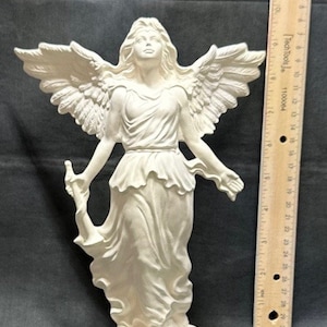 Könnte beinhalten: Weiße Keramikengelfigur mit ausgebreiteten Flügeln, die auf einem Wolkensockel steht. Der Engel trägt ein fließendes Gewand und hat langes Haar. Die Figur ist etwa 30 cm hoch.