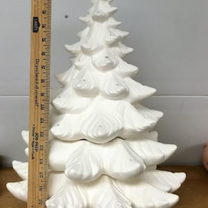 Può includere: Un albero di Natale in ceramica bianca, alto circa 48 cm, con un design dettagliato e stratificato. L'albero ha una classica forma di abete, con rami strutturati e arrotondati. Non è verniciato, pronto per la personalizzazione.