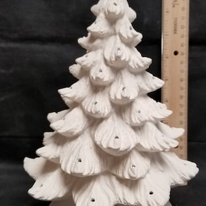 May include: White ceramic Christmas tree with a base and holes for lights. The tree is about 10 inches tall.